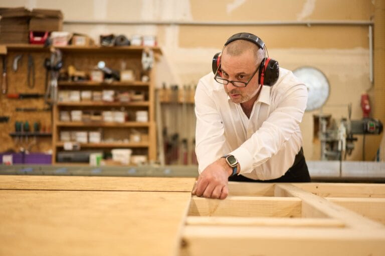 Zimmermann misst Holzelement mit Maßband – handwerksfotografie Stuttgart