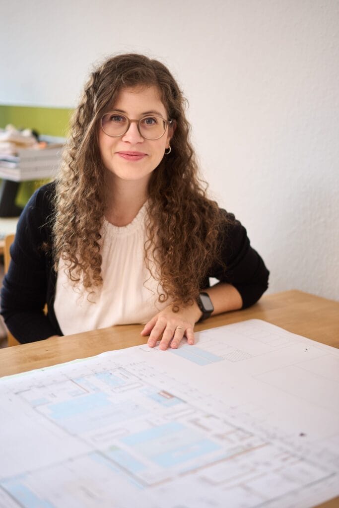 Portrait einer Mitarbeiterin mit Bauplänen – Mitarbeiterportraits, Unternehmensfotografie und Employer Branding in Karlsruhe.
