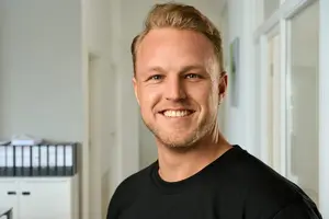 Businessportrait eines lächelnden Mannes im Büroflur – Businessfotografie und Personal Branding in Frankfurt.
