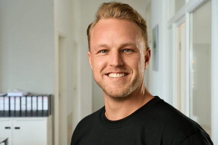 Businessportrait eines lächelnden Mannes im Büroflur – Businessfotografie und Personal Branding in Frankfurt.