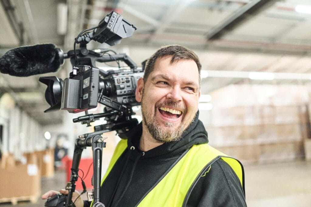 Filmproduktion in der Logistik Mann mit Warnweste und Filmkamera Behind the scences